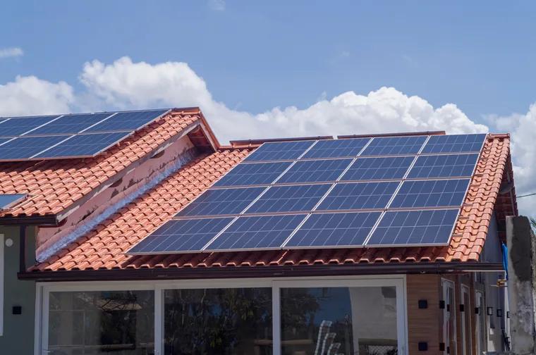 Especialistas analisando a maquete de uma casa com painéis solares