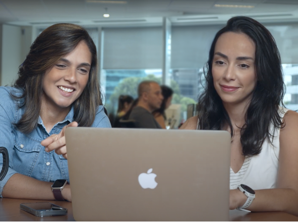 Duas mulheres trabalhando juntas no escritório olhando um notebook