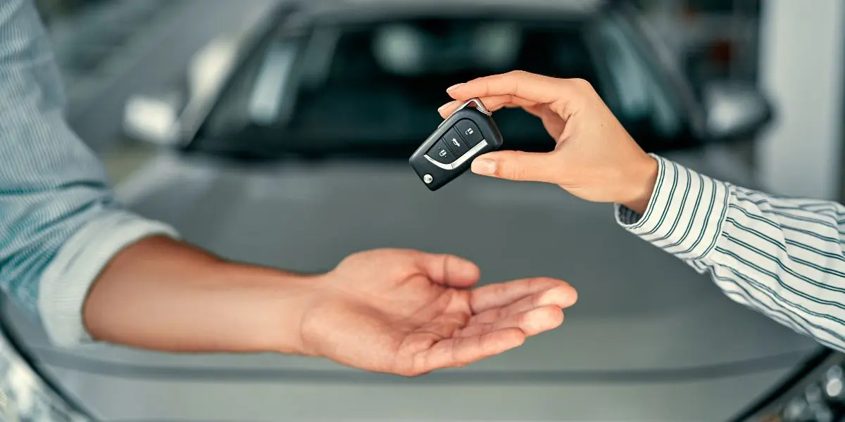 uma pessoa sendo entregue a chave de um carro por outra pessoa